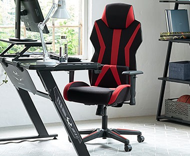Krzesło gamingowe z czerwonymi elementami przy regulowanym biurku 
