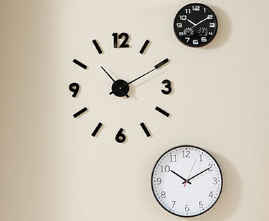 Kompozycja z 3 zegarów na jasno beżowej ścianie