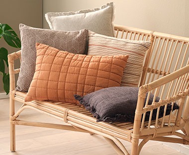 Bambusowa sofa na której leżą kolorowe poduszki ozdobne 