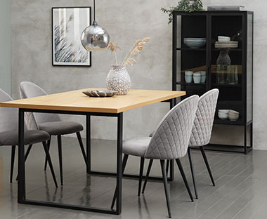 Stół z drewnianym blatem i czarnymi nogami oraz szarymi krzesłami 