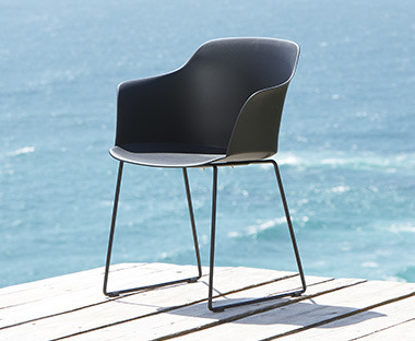 Plastikowe, czarne krzesło na tarasie na tle morza