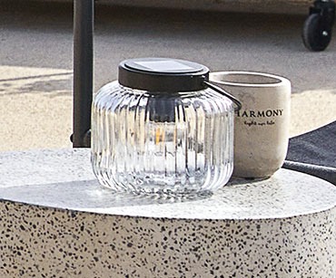 Szklana lampka solarna i betonowa świeczka na cementowym stoliku 