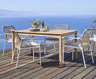 Drewniany stół z 4 krzesłami z zaplatanymi oparciami i białymi nogami 
