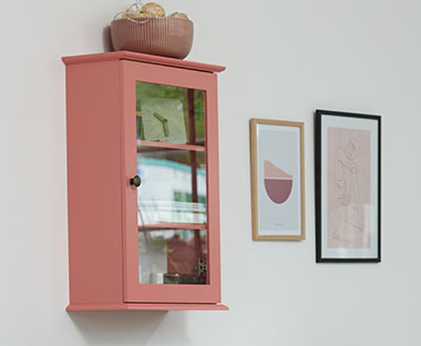 Różowa szafka wisząca z zamykanymi, szklanymi drzwiczkami 