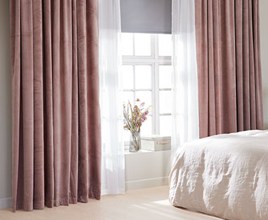 Okno w sypialni z różowymi zasłonami i firankami 