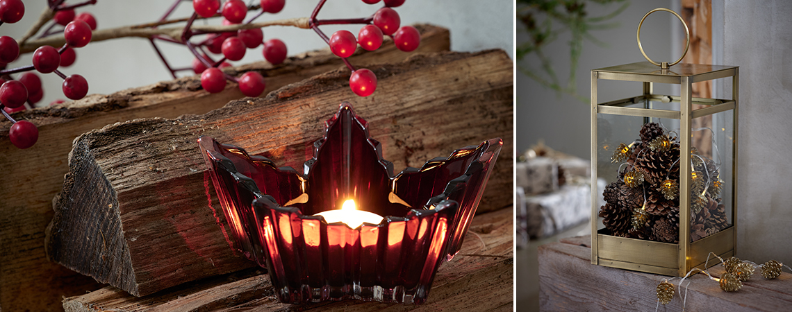 Mały szklany świecznik w kształcie liścia na tle drewna z owocami jarzębiny w tle i złota latarnia z lampkami w środku. 