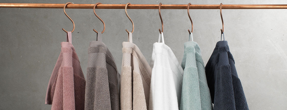 Jednolite ręczniki w różnych kolorach wiszące na haczykach