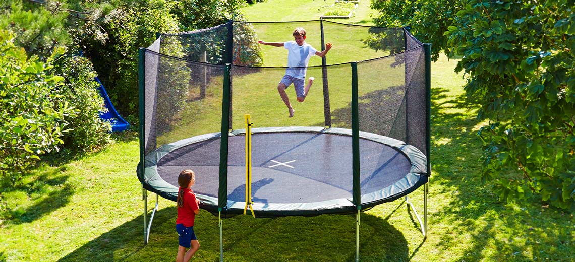Dzieci bawiące się na dużej trampolinie w ogrodzie