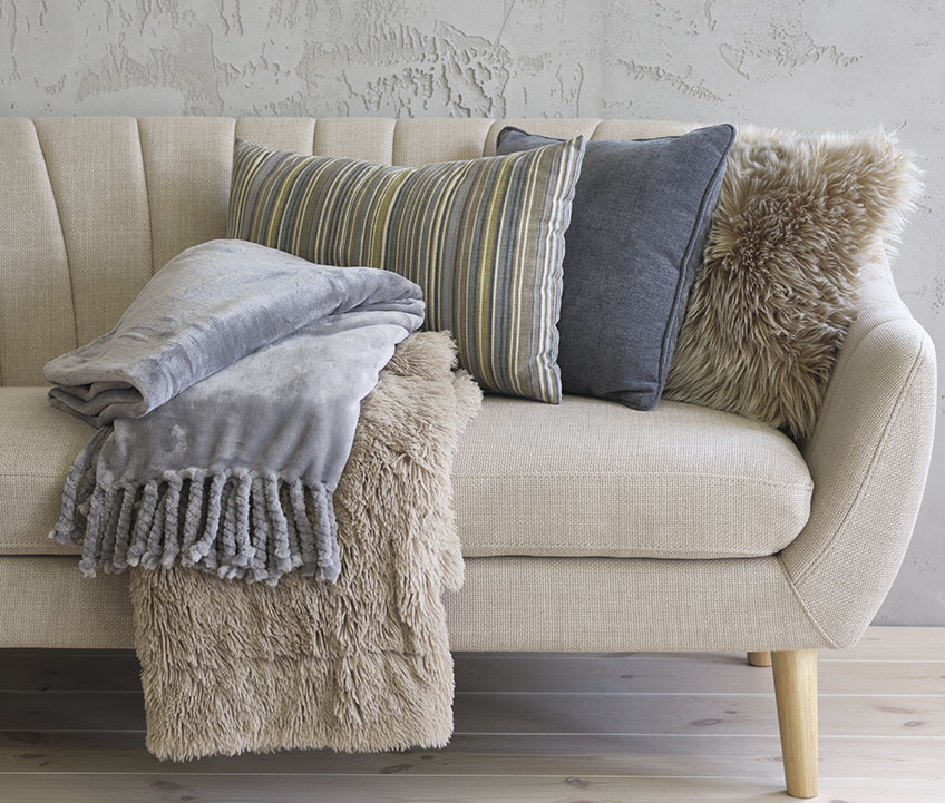 Sofa EGEDAL z niebieską narzutą z polaru BONDEROSE, narzutą ze sztucznego futra MYRFIOL, poduszką w paski KORALLROT, niebieską poduszką HORNFIOL i poduszką ze sztucznego futra TAKS Sofa z narzutą z polaru, narzuta ze sztucznego futra, poduszka w paski, niebieska poduszka, oraz poduszka ze sztucznego futra