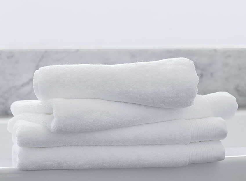 Białe ręczniki ułożone w stos w łazience