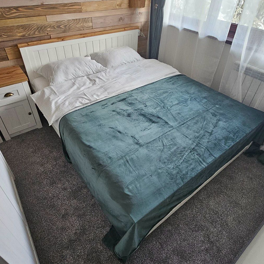 Umeblowany pokój hotelowy z łóżkiem, szafką nocną i białymi zasłonami