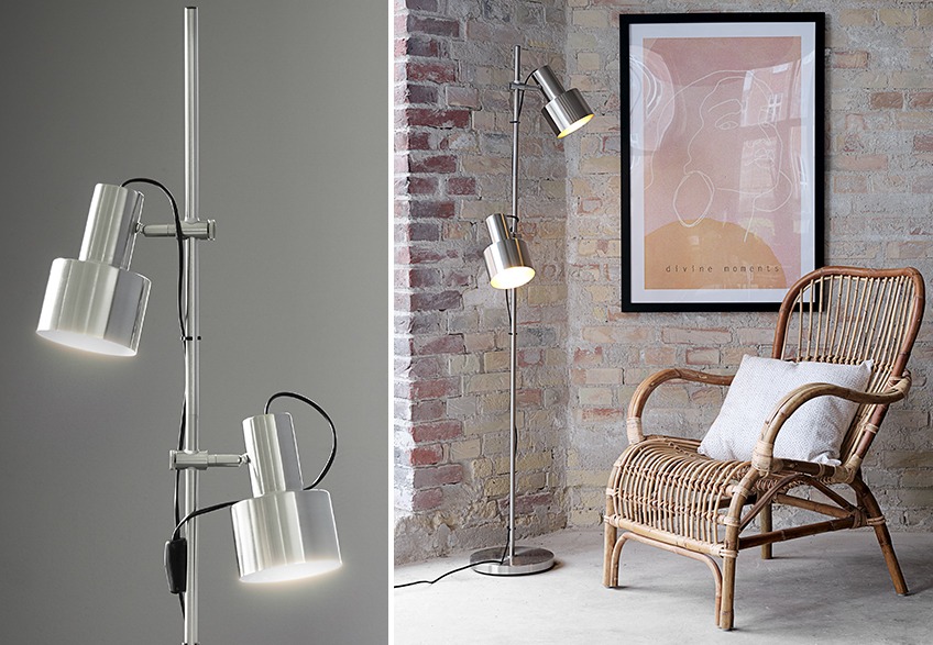 Floor lamp with two lights in a living room with poster in picture frame on the wall and armchair in rattan