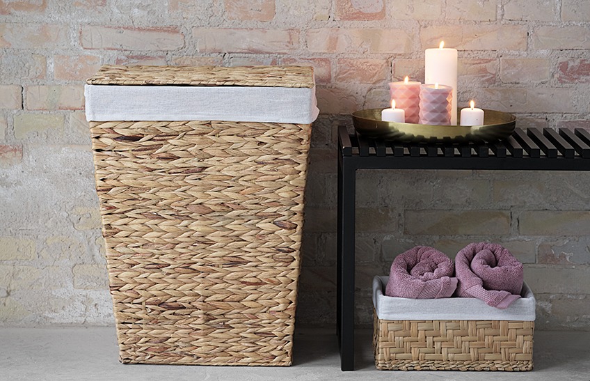 Laundry basket and bench with candles in a bathroom. Basket with towels