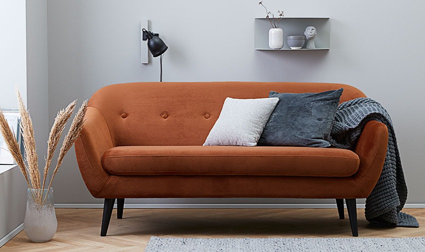 Living room with an orange sofa filled with cushions and a throw