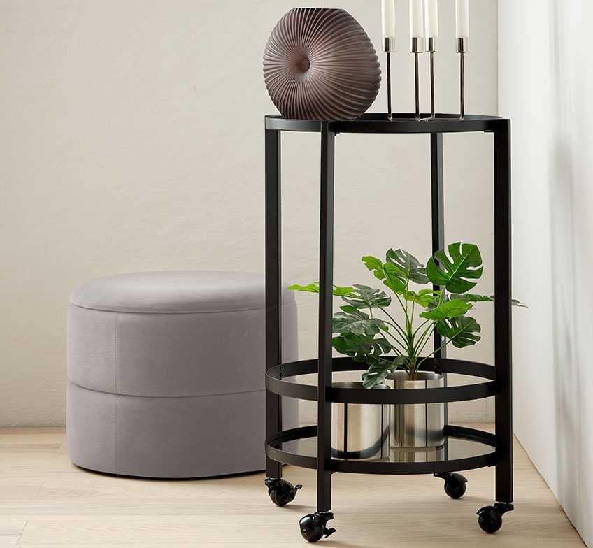 Grey pouffe with storage and a trolley with a vase, candlesticks and a plant pot