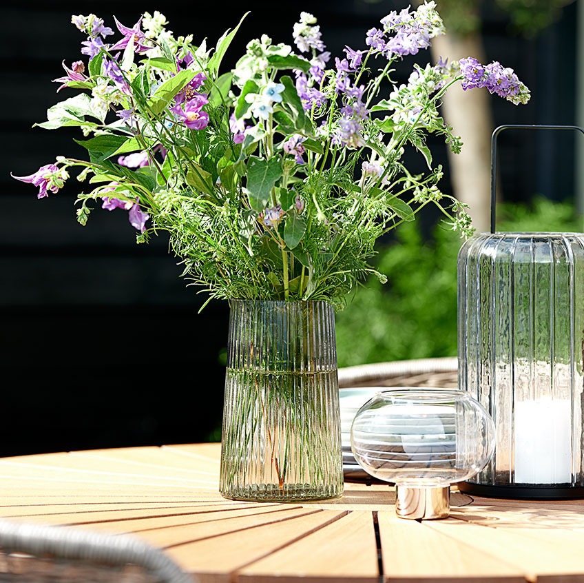 Szklany wazon i latarnie na okrągłym stole ogrodowym