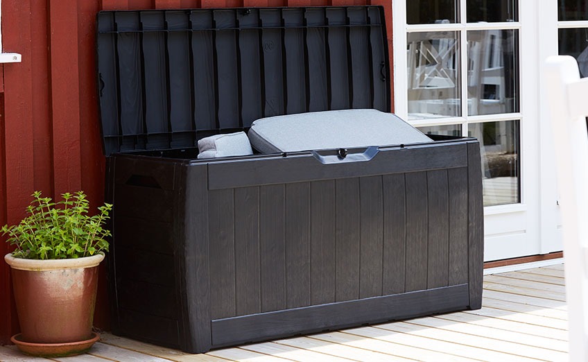 Czarne pudełko na poduszki zewnętrzne z otwartą pokrywą stojące na patio