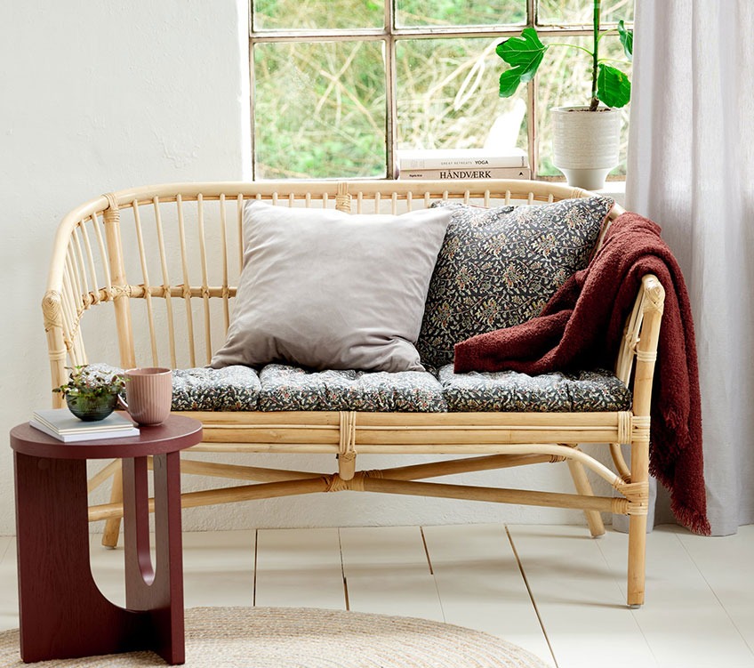 sofa 2-osobowa z rattanu z poduszkami na siedziska i oparciem, bordowym narzutem i okrągłym stolikiem