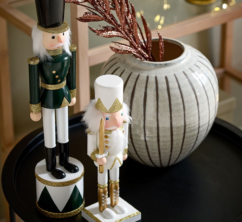 Dwie świąteczne figurki i wazon na czarnym stoliku kawowym 