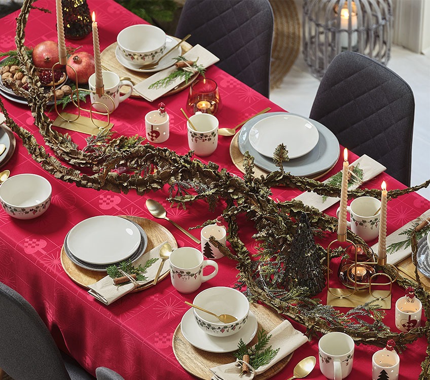 Świąteczny stół z czerwonym obrusem i złotymi dodatkami 