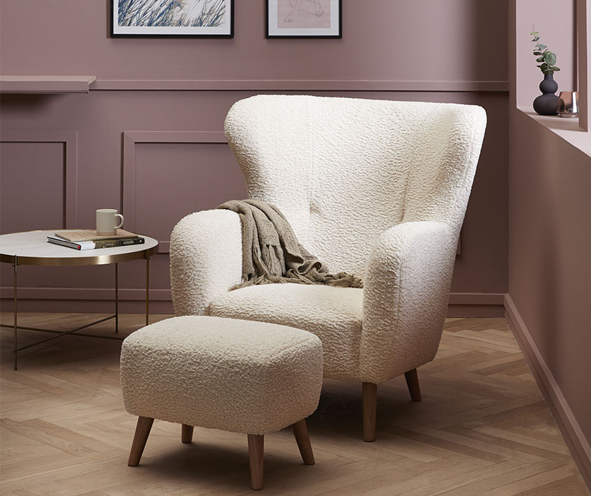 Biały fotel i pufa z miękkiego materiału w stylowym salonie