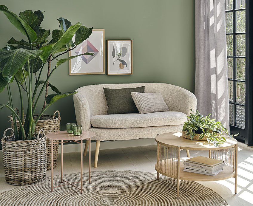 Salon z białą sofą, dębowym stolikiem kawowym i zielonymi roślinami. 
