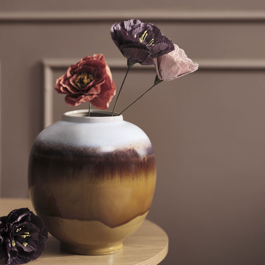 Wielkokolorowy wazon na stoliku i sztuczne rośliny 