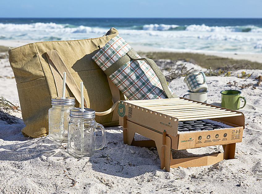 Przenośny grill, torba piknikowa, koc piknikowy i szklanki oraz kubeczki na piasku 
