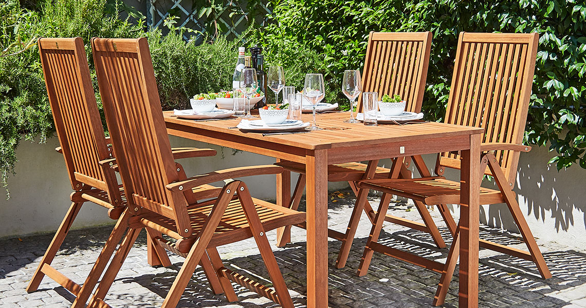 Drewniane krzesła ogrodowe z opcją rozłożenia przy drewnianym stole na tarasie. 