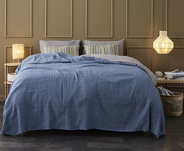 Niebieska narzuta na łóżku w stylowej sypialni